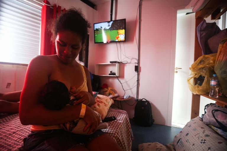 Josefa Cristina amamenta o filho em um quarto de hostel em Camburi