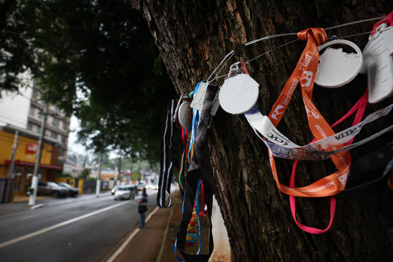 Amigos de Carla Gimenez Fortuna, 55, deixaram medalhas de provas de corrida de rua em árvore na avenida Paes de Barros, na Mooca, perto de onde ela foi atropelada por um carro que invadiu o corredor de ônibus