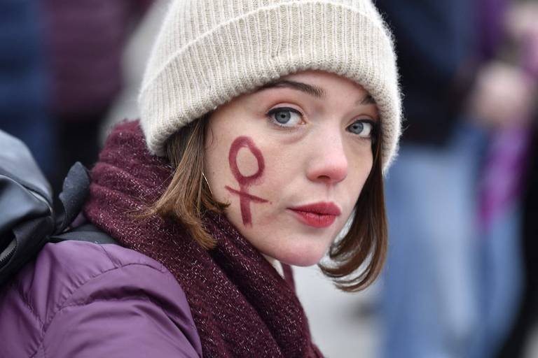 Manifestante com o símbolo do gênero feminino pintado no rosto durante protesto em Paris