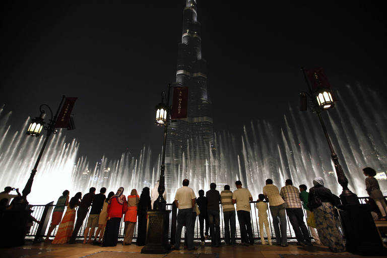 Turistas observam a Dubai Fountain, com o Burj Khalifa ao fundo