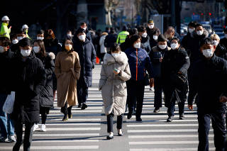FILE PHOTO: Commuters cross a zebra crossing, amid the coronavirus disease (COVID-19) pandemic in Seoul