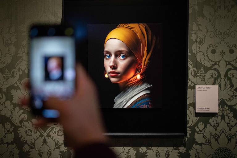 Visitante fotografa tela elaborada com inteligência artificial por Julian van Dieken, inspirada na pintura 'Moça com Brinco de Pérola', de Johannes Vermeer, em exibição no Museu Mauritshuis, em Haia, na Holanda