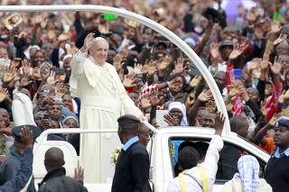 Pope Francis waves to faithful while riding in an open truck as he arrives for a Papal mass in Kenya's capital Nairobi