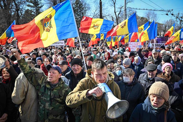 Homem com megafone cercado de multidão com bandeiras de Moldova