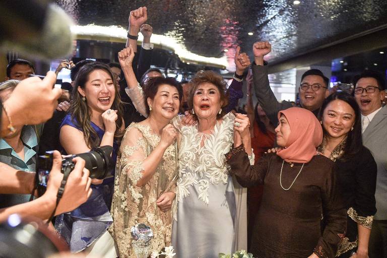 Janet Yeoh (no centro à direita), mãe da atriz Michelle Yeoh, comemorando depois de a filha ganhar o Oscar de melhor atriz, em um evento em Kuala Lumpur, na Malásia