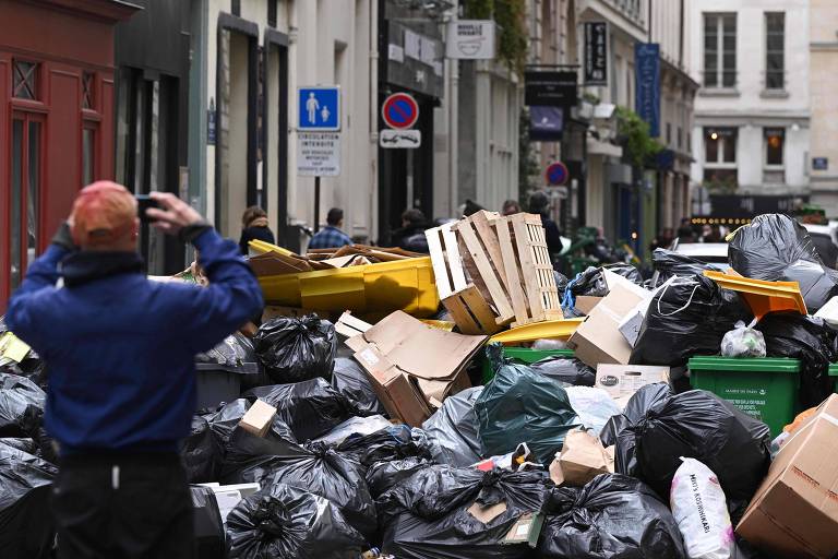 Pedestre tira uma foto do lixo acumulado em uma rua de Paris