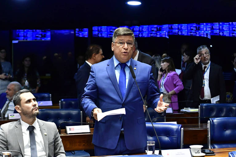 O senador Carlos Viana está de pé, no centro da foto, falando. Ao lado dele, sentado, está o senador Cleitinho