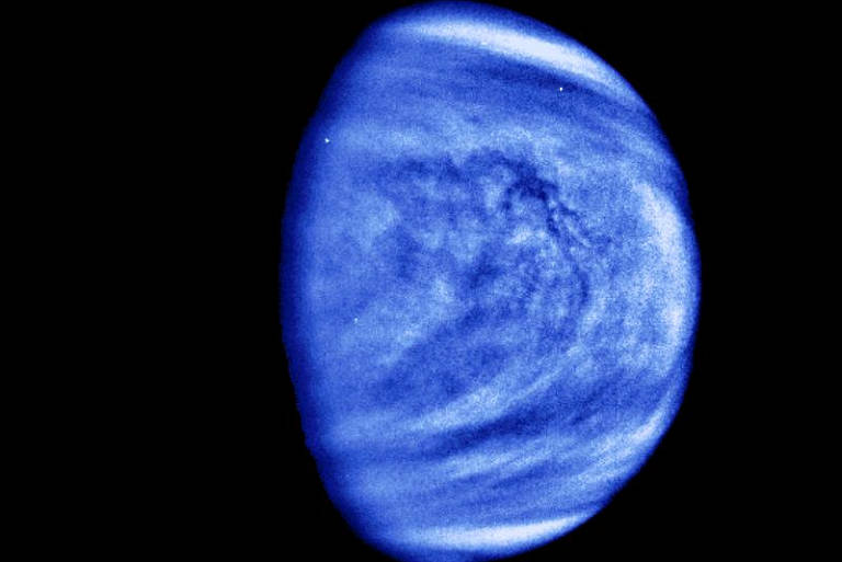 Foto de Vênus feita pela sonda Galileo em 1990; sua atmosfera é ultradensa e dominada por dióxido de carbono, capaz de gerar um efeito estufa tão poderoso que a temperatura na superfície excede os 460°C