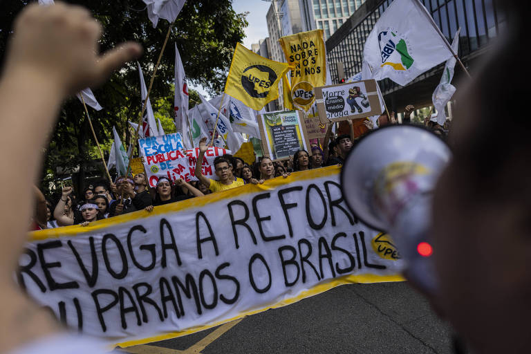 Estudantes seguram faixa em que está escrito regova a reforma ou paramos o Brasil
