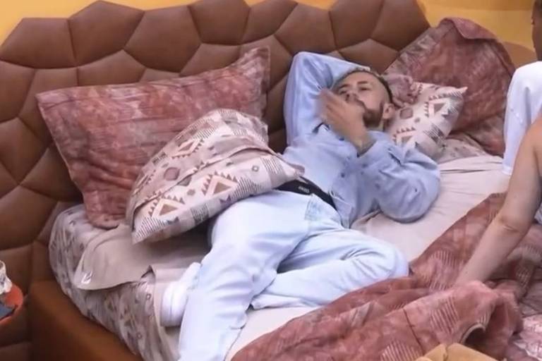 Em foto colorida, homem deita em uma cama e lamenta a eliminação da parceira do jogo