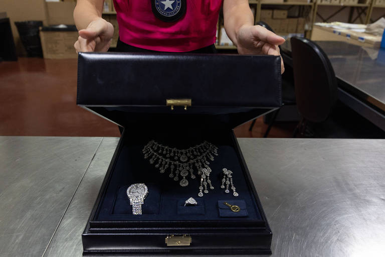 Caixa preta com jóias preciosas é erguida por mãos masculinas de um funcionário da Receita Federal