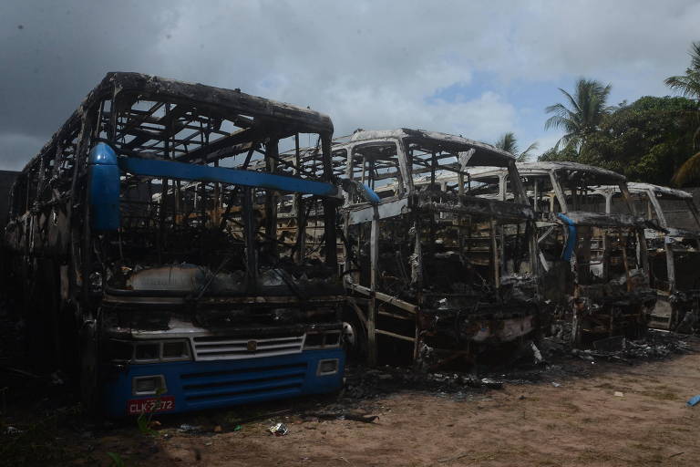 Foto mostra restos de ônibus queimados. só é possível distingui-los por causa das estruturas retorcidas