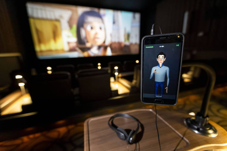 Celular com um aplicativo de Libras, dentro de uma sala de cinema 