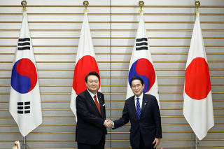 South Korea's President Yoon Suk Yeol shakes hands with Japan's Prime Minister Fumio Kishida in Tokyo