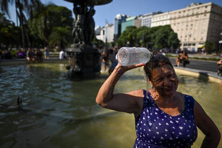 Mulher se refresca com água de fonte pública na avenida 9 de Julho, em Buenos Aires, na Argentina, em meio a onda de calor histórica no país sul-americano