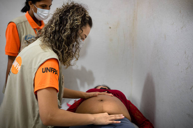 A mulher indígena venezuelana Dennis, deitada de barriga para cima, é atendida por funcionárias do Fundo de População das Nações Unidas em unidade de saúde em  Boa Vista, em Roraima