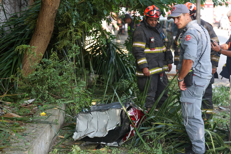 Bombeiros observam pedaço da fuselagem do helicóptero, que caiu no bairro da Barra Funda, zona oeste de São Paulo, deixando quatro mortos