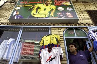 AN IRAQI STANDS IN THE DOORWAY OF HIS SPORTS SHOP IN BAGHDAD