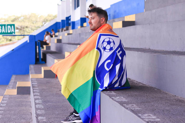 Moisés Spilere no Estádio da Montanha, enrolado em bandeira com as cores do arco-íris e escudo do Caravaggio