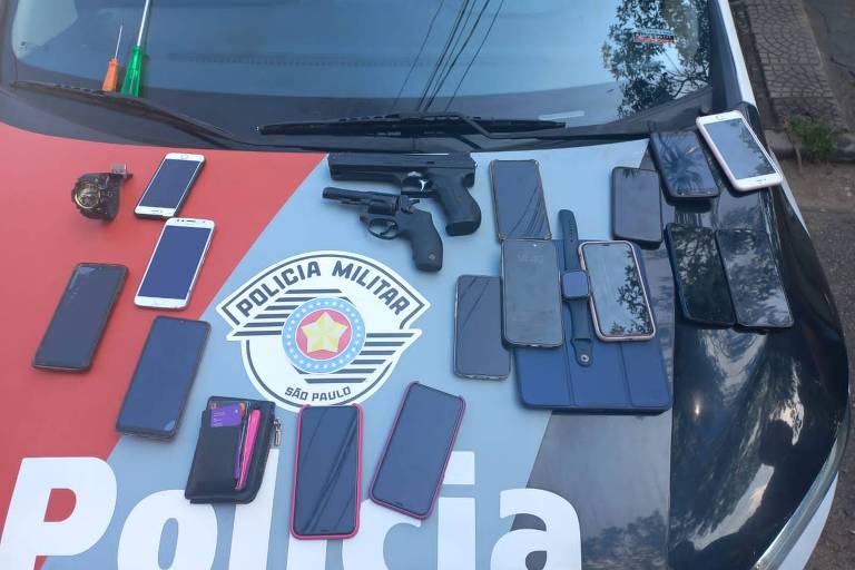 Celulares e armas estão sobre capô do carro da Polícia Militar