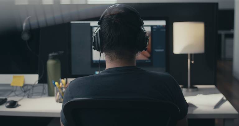 Homem em frente a computador com headphone