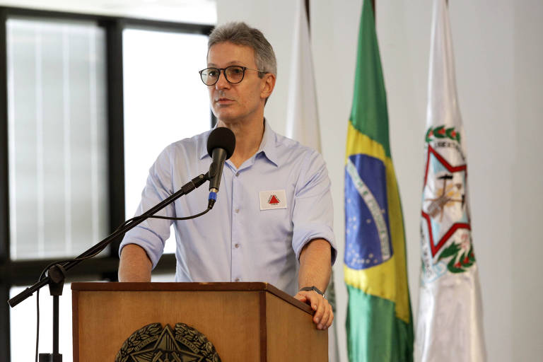 A foto mostra o governador de Minas Gerais, Romeu Zema (Novo), de pé, tendo à sua frente um microfone