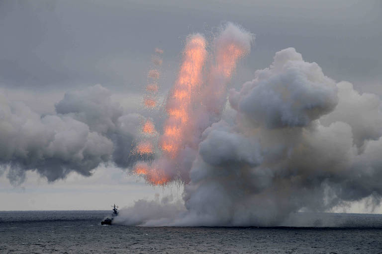 mísseis são vistos saindo de navio no mar, com muita fumaça no entorno