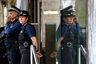 Police officers stand outside New Scotland Yard, the headquarters of the Metropolitan Police, in London