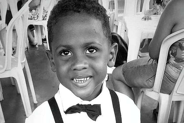 A imagem mostra uma criança sorrindo, usando suspensório e gravata borboleta