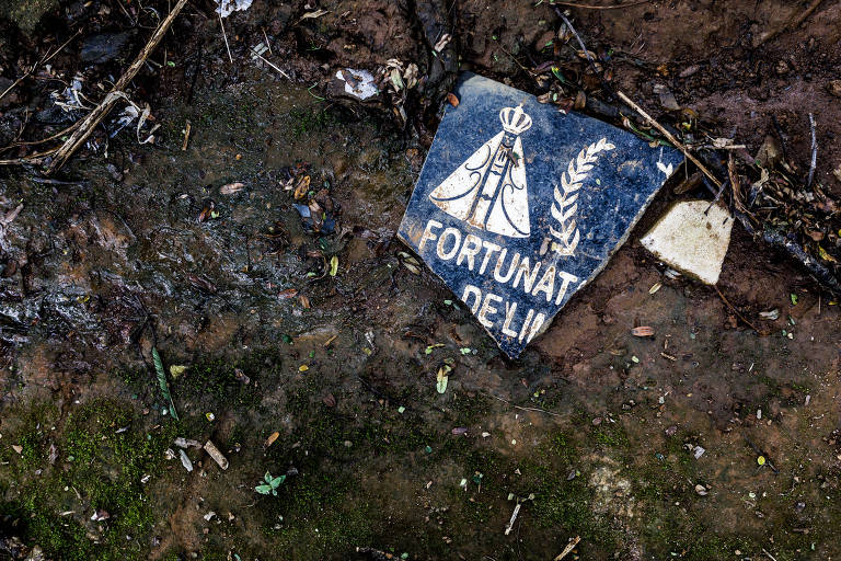 Foto de uma lapide quebrada no chão do cemitério