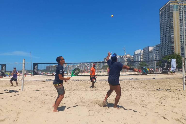 dupla de homens jogam beach tennis na praia