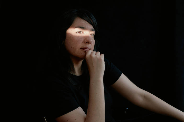 mulher com camiseta preta e luz realçando os olhos