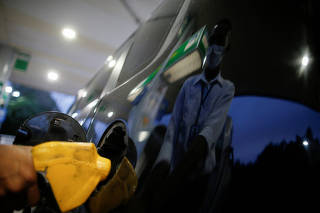FILE PHOTO: A worker uses a petrol pump at a Brazilian oil company Petrobras gas station in Brasilia