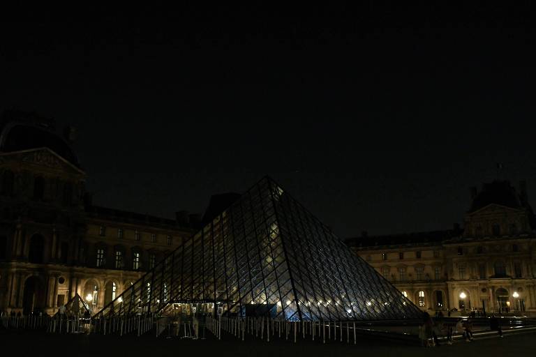 Pirâmide de vidro na área externa do museu do Louvre com as luzes apagadas