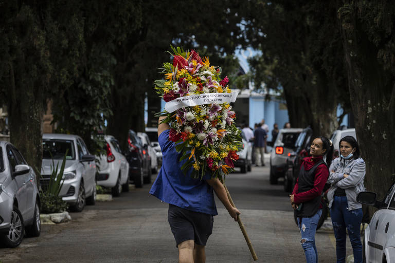Homem carrega coroa de flores no velório da professora Elisabeth Tenreiro, no cemitério do Araçá; docente foi morta por aluno de 13 anos na Escola Estadual Thomazia Montoro, na Vila Sônia, zona oeste