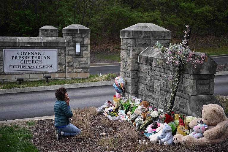 a imagem mostra uma mulher ajoelhada, de mãos unidas, rezando em frente a um memorial com flores, bonecos e ursos de pelúcia. em segundo plano, é possível ver uma placa que indica a localização da foto: Covenant Presbyterian Church