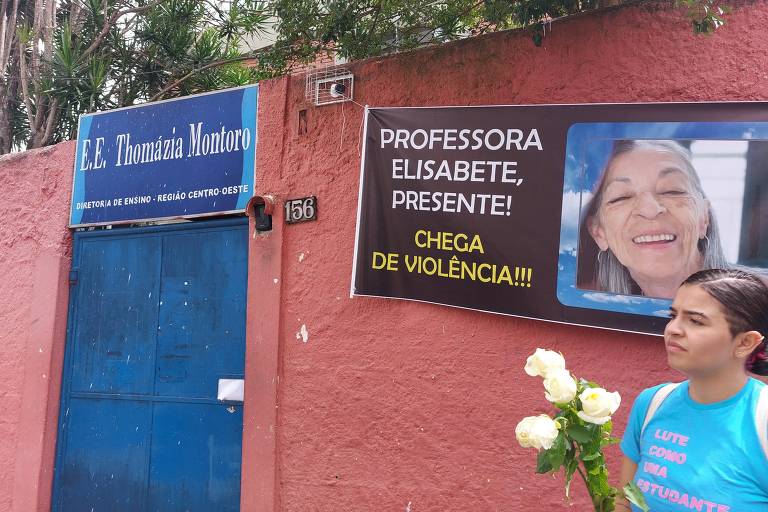 Estudante com rosas brancas em frente a uma faixa com os dizeres 'Professora Elisabeth, presente' e 'Chega de Violência' 
