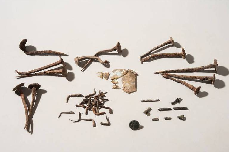 Parte do conteúdo encontrado na cremação primária em Sagalassos: alguns dos 'pregos mortos', uma moeda, restos queimados de um osso, unhas comprimidas e cacos de vidro