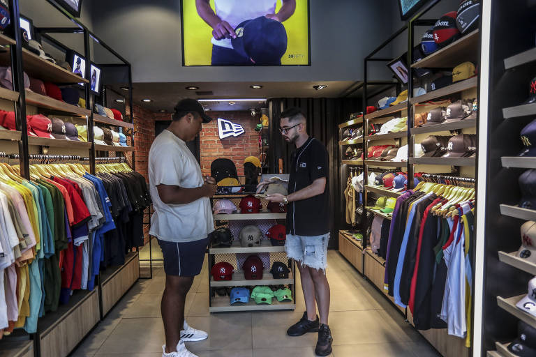 Matheus Gustavo (à esq.) na loja da New Era, no Rio de Janeiro; "Aqui curtimos mais o futebol"