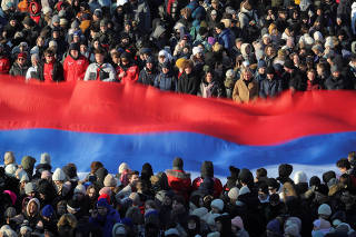 People hold a Russian national flag during a rally dedicated to the Defender of Fatherland Day in  Saint Petersburg