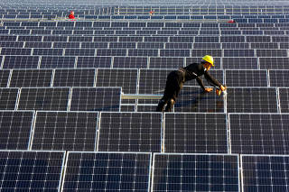 FILE PHOTO: Man works on solar panels at a solar power plant of China Huaneng Group in Huaiyin