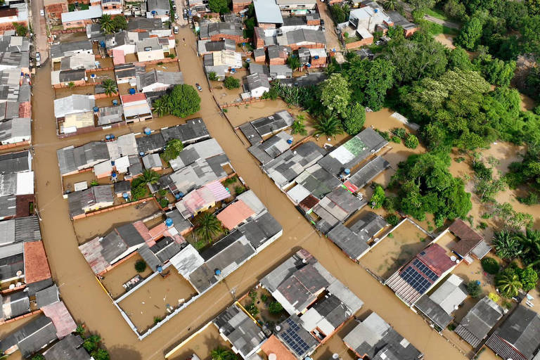 Imagem aérea de bairro de Rio Branco, no Acre, em que a água barrenta chega até o telhado das casas