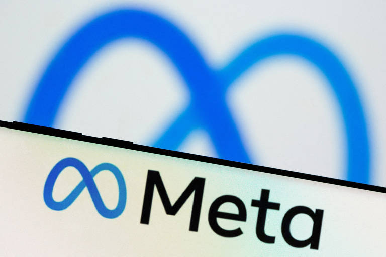 Logo da Meta, holding dona do Facebook e do Instagram, é visto atrás de um smartphone com outro logo da empresa