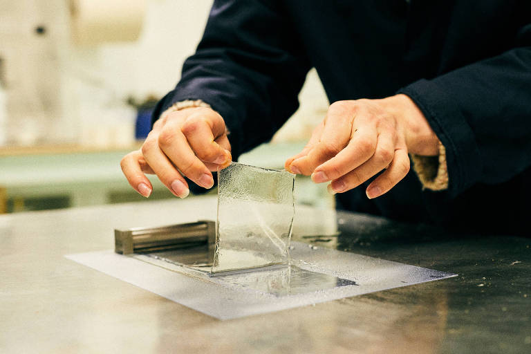 Membrana de plástico comestível feita de algas é segurada por um par de mãos em uma fábrica 