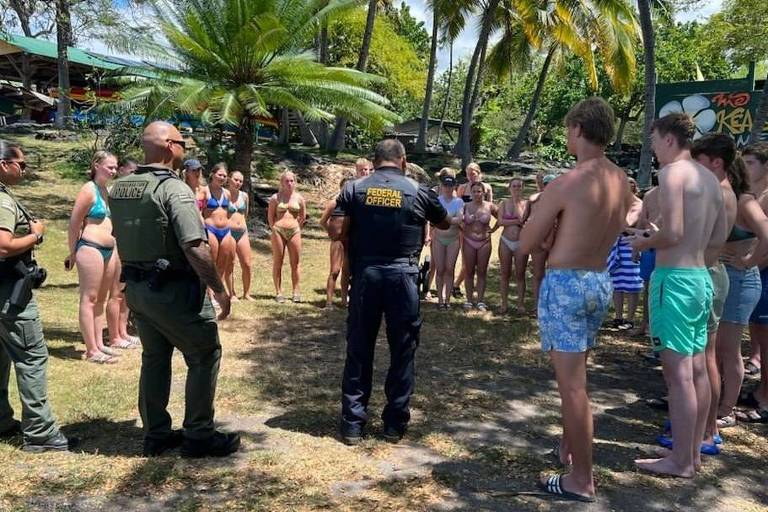 a foto mostra policiais conversando com um grupo de pessoas numa praia