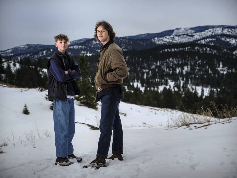 Badge (à esq.) e Lander Busse agasalhados sobre a neve em uma montanha; eles entraram com ação judicial contra o Estado de Montana