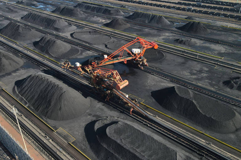 Foto aérea de uma máquina movendo grandes quantidades de carvão