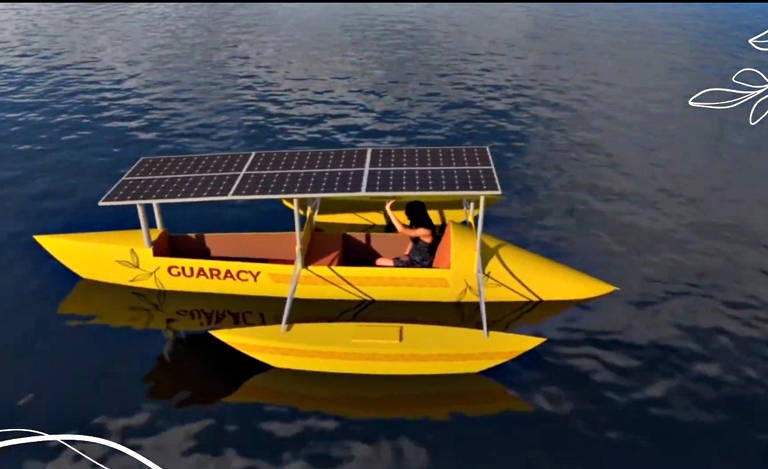 Imagem colorida mostra um barco feito em computador, na cor amarela, com um casco maior ao meio e dois menores nas laterais. Ele tem um painel solar na parte de cima.