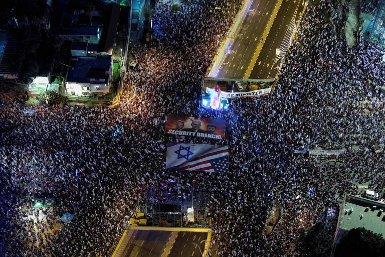 Vista aérea mostra multidão segurando cartazes e bandeiras