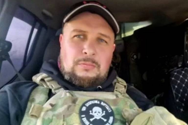 Foto colorida mostra homem russo com roupa militar com um broche de caveira